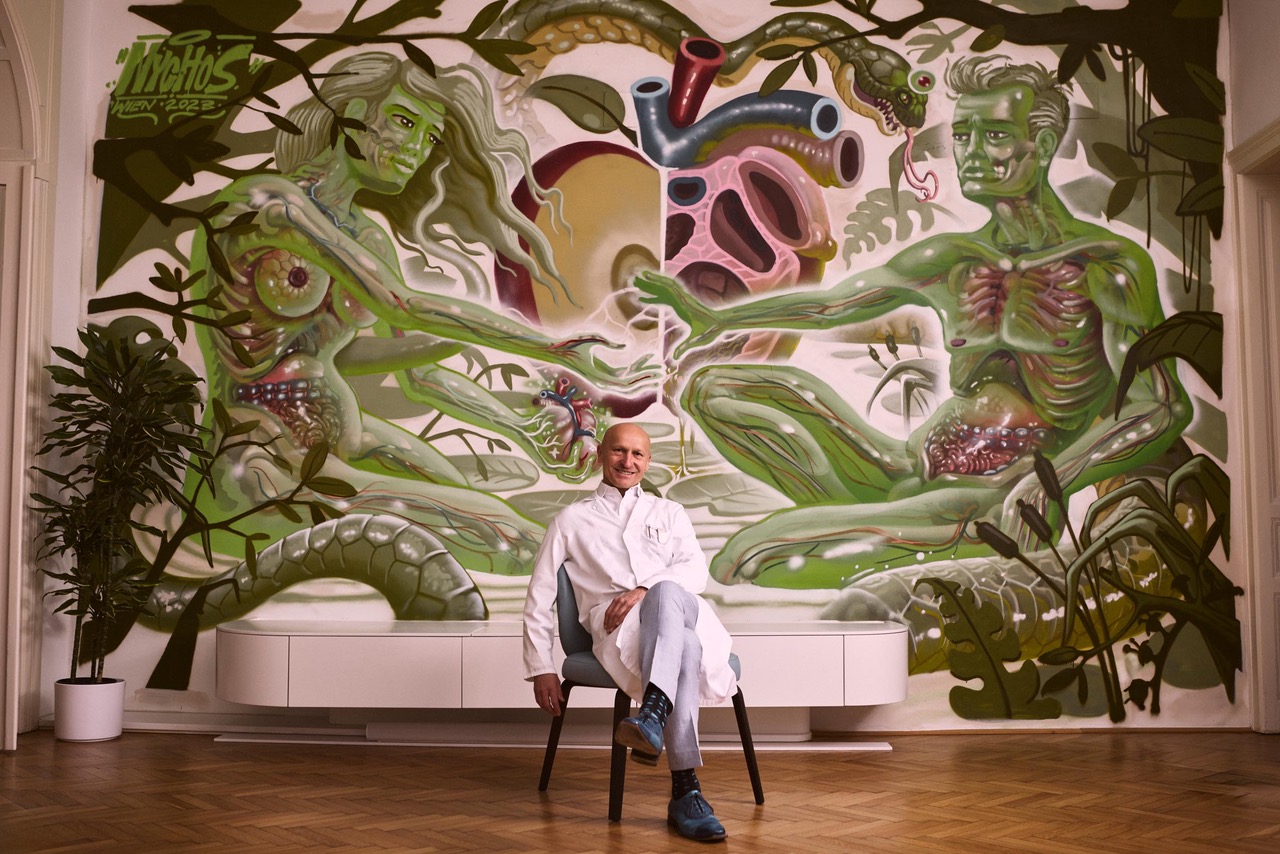 Univ.-Prof. Dr. Gerhard Prager sitzend vor dem Mural im AKH Wien